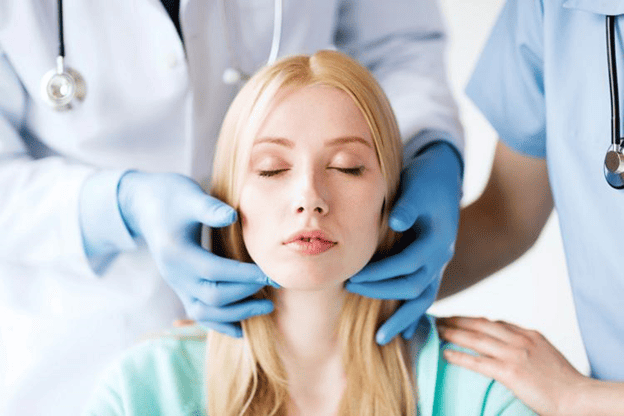 Woman having her facial features assessed by healthcare professionals as part of a personalized medical spa treatment plan.